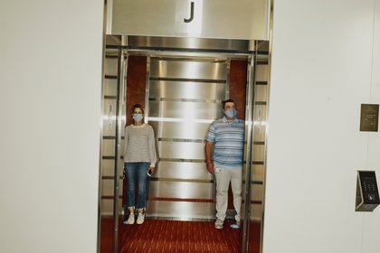 Dos empleados de Boston Properties demuestran un distanciamiento seguro en un ascensor en el Centro Prudential de Boston el 22 de junio de 2020. (Tony Luong/The New York Times)