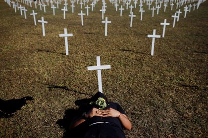 Un activista yace junto a las cruces que simbolizan a los que murieron a causa de la enfermedad del coronavirus (COVID-19) frente al Congreso Nacional durante una protesta contra Bolsonaro, este domingo en Brasilia (REUTERS / Adriano Machado)