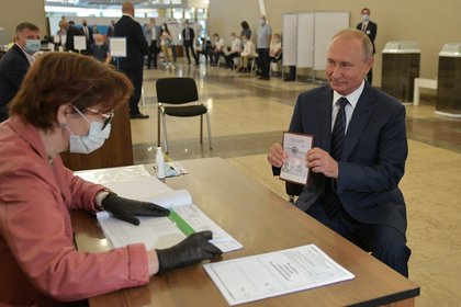 Vladimir Putin muestra su documento en la mesa de votación (Reuters)