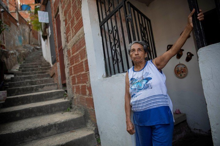 Hilda Márquez, en la entrada de su casa del barrio Guaicaipuro de Catia, en Caracas. Extraña a su hijo, que se fue a Chile, y depende de sus remesas para vivir. /EFE