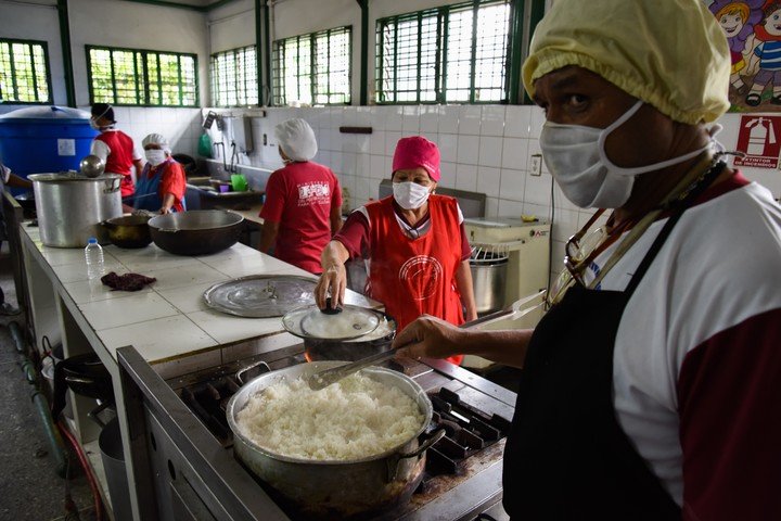 Empleados médicos preparan almuerzos para repartir a los chicos de una escuela del sur de Caracas, en plena cuarentena por la pandemia. /XINHUA
