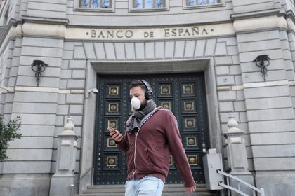 FILE PHOTO: A man wears a protective face mask as he walks past Banco de Espana (Bank of Spain), amidst concerns over coronavirus outbreak, in Barcelona, Spain March 14, 2020. REUTERS/Nacho Doce/File Photo