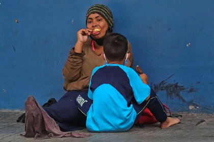 Una mujer y un niño permanecen sentados en una calle en la que piden dinero este miércoles en Tegucigalpa (Honduras). EFE/ Gustavo Amador 
