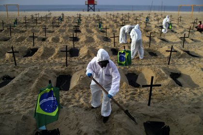Activistas de la ONG Río de Paz con equipo de protección cavan tumbas en la playa de Copacabana para simbolizar a los muertos por la enfermedad del coronavirus (COVID-19) durante una manifestación en Río de Janeiro, Brasil, 11 junio 2020.REUTERS/Pilar Olivares