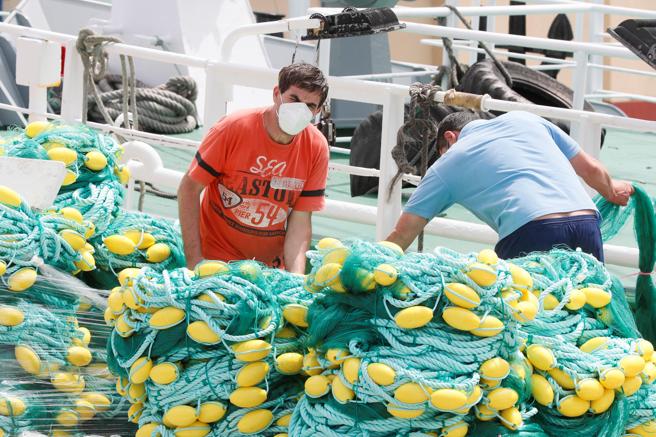 Pescadores preparan las redes en el puerto del pueblo de Burela, Lugo