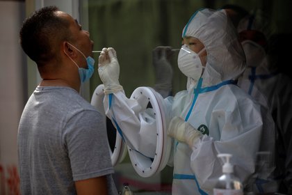 Un trabajador médico que lleva un traje protector completo examina a un hombre para determinar si sufre la enfermedad de COVID-19 en el Hospital Puren de Beijing, China. EFE/EPA/WU HONG 
