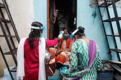 Voluntarios comunitarios de salud controlan la temperatura de una mujer durante una campaña de control de coronavirus en un barrio pobre de Mumbai, India, el 16 de agosto de 2020. (REUTERS / Francis Mascarenhas)