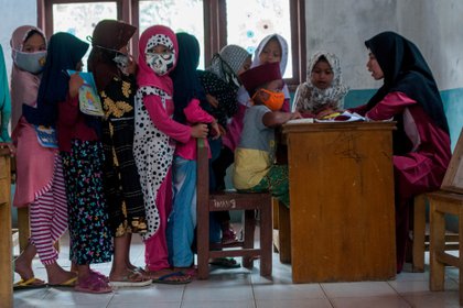 Niños con mascarillas protectoras hacen fila durante las actividades de enseñanza y aprendizaje en medio del brote de coronavirus en Lebak, provincia de Banten, Indonesia (Reuters)