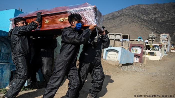 Trabajadores del cementerio de Comas, en el norte Lima, transportan ataúdes de personas fallecidas por COVID-19.