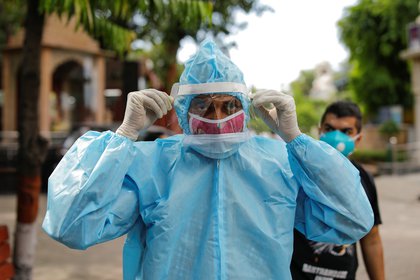 Un hombre que usa equipo de protección personal (PPE) ajusta su protector facial antes de la cremación de un familiar que murió debido a la enfermedad coronavirus (COVID-19), en un crematorio en Nueva Delhi, India, el 22 de agosto de 2020. REUTERS/Adnan Abidi