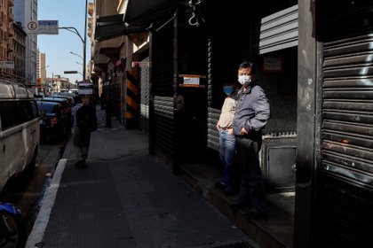 Personas con tapabocas caminan frente a tiendas cerradas en San Pablo (EFE)