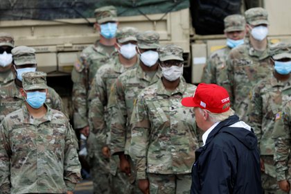 El presidente Donald Trump camina frente a los miembros de la Guardia Nacional que trabajan en las tareas de emergencia provocadas por el Huracán Laura. REUTERS/Tom Brenner