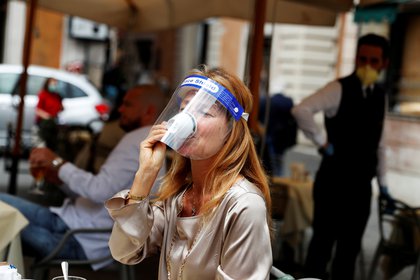 Una mujer con una máscara toma un café en un bar de Roma tras el levantamiento de las restricciones en mayo (REUTERS/Yara Nardi)