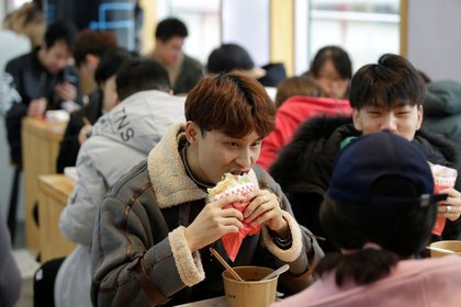 Un joven come un bocadillo de pollo en una cadena de comida rápida en Beijing (REUTERS/Jason Lee)