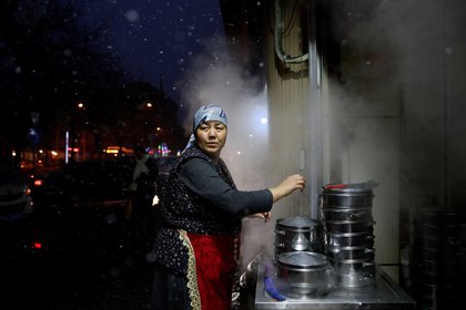 Una mujer de la minoría étnica musulmana uigur atiende a su puesto de comida en la ciudad de Urumqi, en la región autónoma Uigur de Xinjiang, China. (EFE/ How Hwee Young/Archivo)