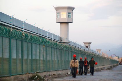 Trabajadores caminan junto a la valla perimetral de lo que se conoce oficialmente como centro de formación profesional en Dabancheng, en la Región Autónoma Uigur de Xinjiang (China), el 4 de septiembre de 2018. REUTERS/Thomas Peter