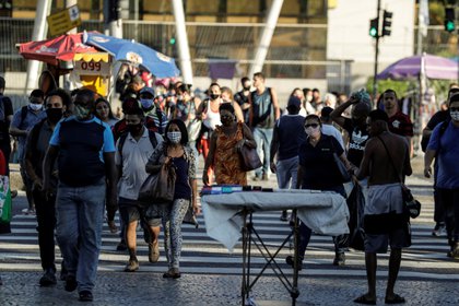 Personas con mascarillas para prevenir la propagación del coronavirus cruzan una calle en Río de Janeiro (Brasil). EFE/Antonio Lacerda/Archivo 