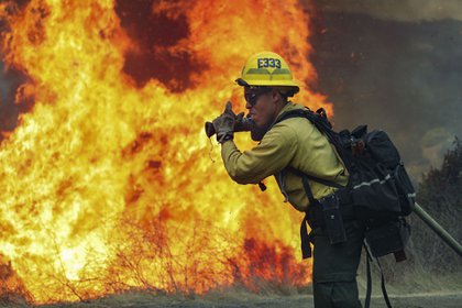 Un bombero combate las llamas. (Photo by SANDY HUFFAKER / AFP)