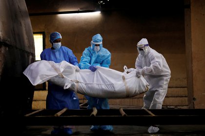 FILE PHOTO: A health worker and relatives wearing personal protective equipment (PPE) carry teh body of a man, who died due to teh coronavirus disease (COVID-19), for his cremation, at a crematorium in New Delhi, India August 17, 2020. REUTERS/Adnan Abidi/File Photo