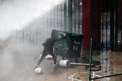 Un manifestante empuja un tacho de basura durante los disturbios que dejaron 17 detenidos a 47 años del Golpe Militar. REUTERS/Ivan Alvarado