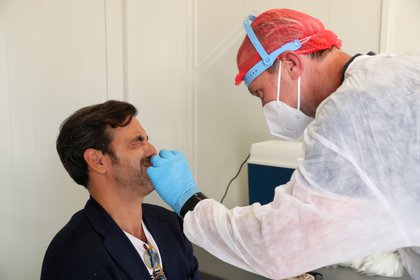 Un trabajador de la salud toma una muestra de hisopo de un hombre para realizar una prueba de la enfermedad por coronavirus (COVID-19), en un centro de pruebas de COVID-19 dentro de las instalaciones del aeropuerto Zaventem de Bruselas (REUTERS / Yves Herman)