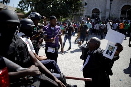Un abogado se arrodilla ante los agentes de la Policía Nacional de Haití (PNH) en el exterior de la iglesia de Saint Pierre durante una ceremonia religiosa organizada por el Colegio de Abogados para honrar a Monferrier Dorval, asesinado el 28 de agosto en Puerto Príncipe, Haití, el 18 de septiembre de 2020 (REUTERS/Andrés Martínez Casares)