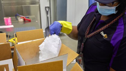 Un empleado de FedEx distribuye hielo seco para el envío de vacunas