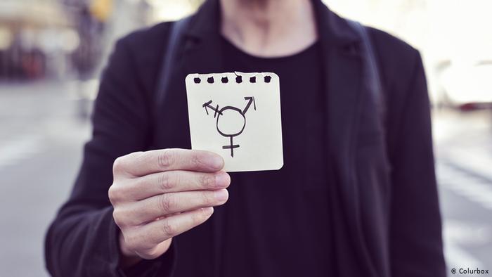 Foto simbólica de una persona que muestra el símbolo trans en un papel 