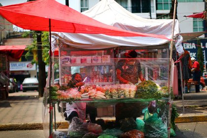 Vendedores en un mercado local son vistos detrás de una barrera protectora de plástico como medida para prevenir el contagio de coronavirus en Ciuidad de México, México. 1 de junio de 2020. REUTERS/Edgard Garrido