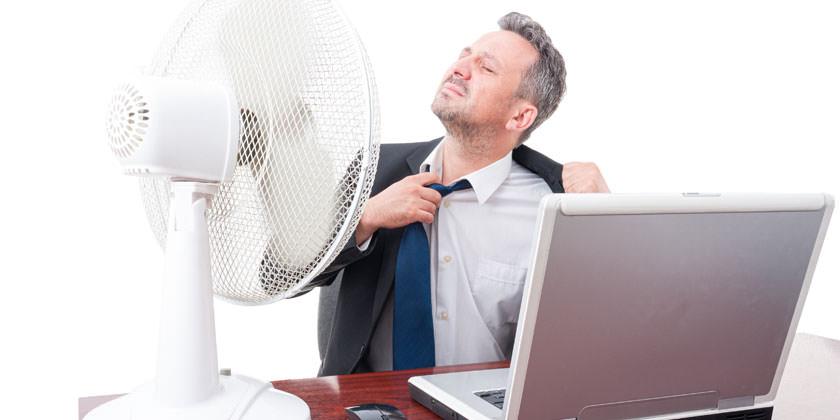Un hombre frente a su ventilador en el puesto de trabajo