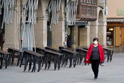 Una mujer con mascarilla camina frente a la terraza de un bar cerrado tras las restricciones al movimiento impuestas por la Diputación Foral de Navarra para tratar de contener la propagación de la COVID-19, en Pamplona, Navarar, España, el 22 de octubre de 2020. REUTERS/Vincent West