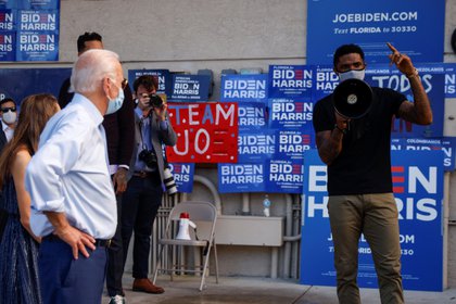 Biden escucha a otro jugador de básquetbol, Udonis Haslem, hablar durante su acto de campaña. Foto: REUTERS/Brian Snyder