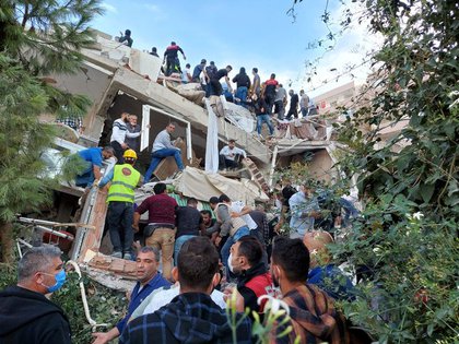 Lugareños y funcionarios buscan sobrevivientes en un edificio derrumbado después de que un fuerte terremoto golpeó el mar Egeo el viernes y se sintió tanto en Grecia como en Turquía, donde algunos edificios colapsaron en la provincia costera de Izmir, Turquía