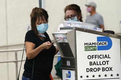 Una mujer deposita un voto por correo en Miami. Cada estado tiene sus propias reglas y plazos para el proceso electoral (AP)