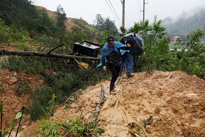 Hombres cruzan un deslizamiento de tierra que bloquea una carretera tras el paso de la tormenta Eta, en Purulha, Guatemala (Reuters)