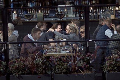 ARCHIVO - En esta imagen de archivo del 4 de abril de 2020, una pareja ríe y se abraza mientras come en un restaurante en Estocolmo. (AP Foto/Andrés Kudacki, Archivo)