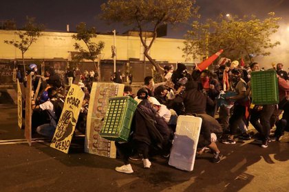 Manifestantes intentan protegerse de los disparos de perdigones de la policía en Lima (Reuters)