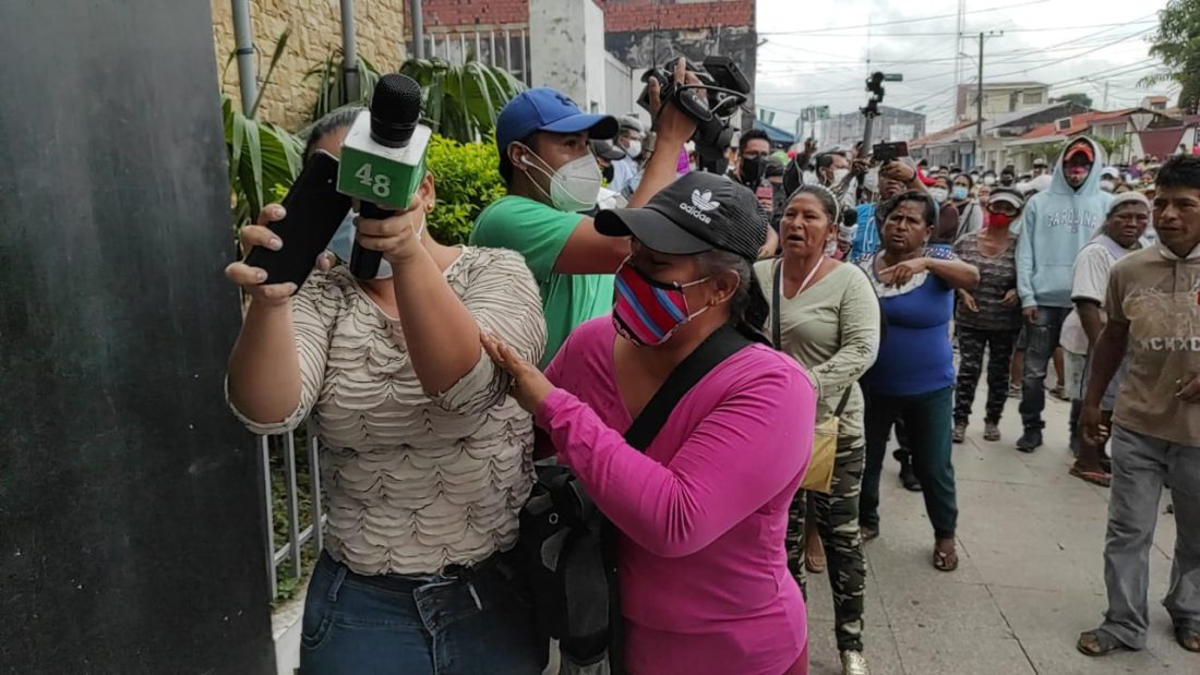 La periodista de Canal 48 de la ciudad de Montero, Vivian Pérez, trata de protegerse del ataque de padres de familia que reclamaban un bono escolar en especie. Diario Zona Norte de Montero