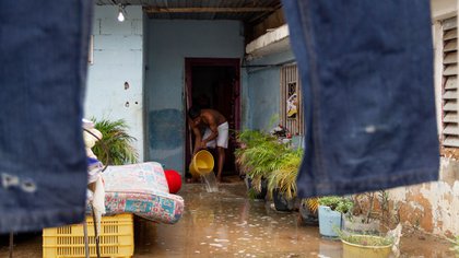 Un hombre saca agua de su casa en Maracaibo (EFE/ Henry Chirinos)