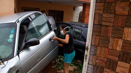 Una mujer revisa un vehículo que fue arrastrado y dañado por la lluvia en Maracaibo (EFE/ Henry Chirinos)