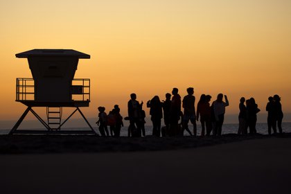 Jóvenes sin máscara que no respetan el distanciamiento social se reúnen en una playa para pasar el rato después de la puesta de sol durante el brote de la enfermedad coronavirus (COVID-19) en Encinitas, California (REUTERS/Mike Blake)