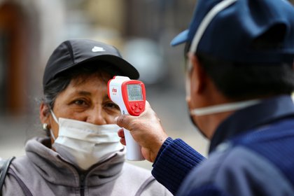 Una mujer con tapabocas es vista mientras le miden la temperatura en Quito (EFE/José Jácome/Archivo)