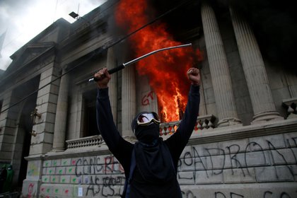 Un hombre protesta en frente del Congreso de Guatemala en llamas ocasionado por manifestantes que protestan contra del Gobierno del presidente, Alejandro Giammattei hoy en Ciudad de G. EFE/Esteban Biba 