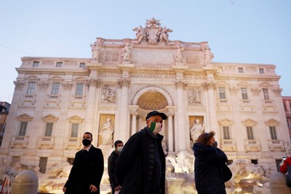 Italianos con máscaras faciales caminan frente a la Fontana di Trevi antes de Navidad bajo las restricciones por el COVID-19 en Roma el 17 de diciembre de 2020. REUTERS/Yara Nardi