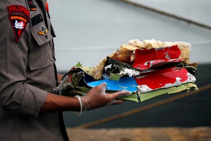 Un oficial carga restos hallados en el mar (Reuters)