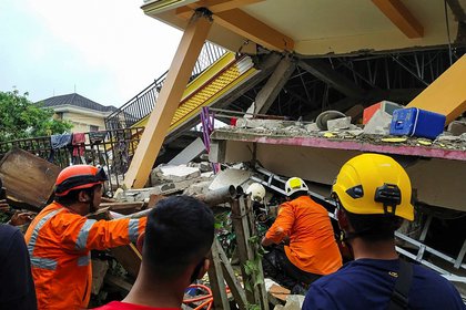 Rescatistas buscando víctimas bajo los escombros de un edificio derrumbado tras un terremoto de 6.2 en Mamuju, Sulawesi Occidental, Indonesia, el 15 de enero de 2021 