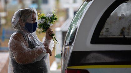 Una mujer deja un ramo de flores a una víctima (MICHAEL DANTAS / AFP)