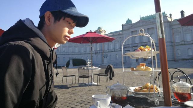 Morimoto desayunando en una plaza.