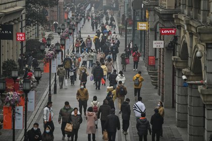 Personas caminan en una calle peatonal de Wuhan. (Hector RETAMAL / AFP)