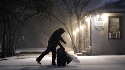 Un hombre caminando en la noche nevada de San Antonio, Texas (AP Photo/Eric Gay)